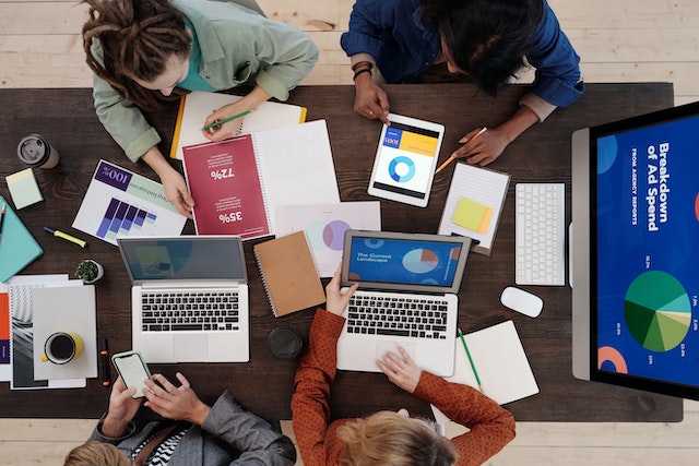 Group of people at a table going over charts and graphics on their computers